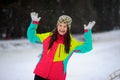 Winter portrait of the young woman in bright ski suit and a knitted cap.