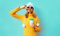 Winter portrait young woman with coffee cup showing peace gesture wearing yellow knitted sweater, white hat with pom pom Royalty Free Stock Photo