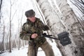 An employee of the national park in green camouflage clothes sets a camera trap on a tiger or leopard in a birch forest