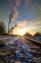 Winter railway to factory in sunset rays.