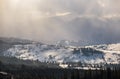 Winter remote alpine mountain village outskirts, countryside hills, groves and farmlands in beautiful sunlight