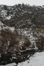 Winter river flows beneath towering basalt columns at the Symphony of Stones, snow-covered cliffs and bare trees create Royalty Free Stock Photo