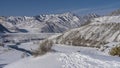 Winter river in a snowy valley. Steam is visible above the unfrozen part of the riverbed. Royalty Free Stock Photo