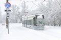 Winter road in Moscow, Russia. Frozen modern tram runs past traffic signs on snowy street. Cold and snowfall in city Royalty Free Stock Photo