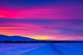 Winter road with mountain during amazing vivid saturated beautiful sunset sky in pink, purple and blue colors. Sunset background