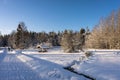 Winter road near woods. Wooden table with benches for rest covered with snow. Path trail with lanterns. Royalty Free Stock Photo