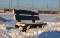 Winter roadside black bench. Snow-covered blask bench