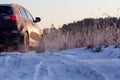Winter rough frozen road in countryside with drifting car on slippery surface
