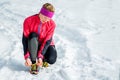 Winter runner getting ready running tying shoe laces. Beautiful fitness model training outside. Copy space on snow Royalty Free Stock Photo