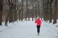 Winter running in park: happy active woman runner jogging in snow, outdoor sport and fitness Royalty Free Stock Photo