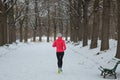 Winter running in park: happy active woman runner jogging in snow, outdoor sport and fitness Royalty Free Stock Photo