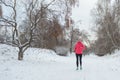 Winter running in park: happy active woman runner jogging in snow, outdoor sport and fitness Royalty Free Stock Photo