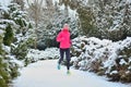 Winter running in park: happy woman runner jogging in snow, outdoor sport and fitness Royalty Free Stock Photo