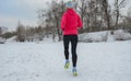 Winter running in park: happy woman runner jogging in snow, outdoor sport and fitness Royalty Free Stock Photo
