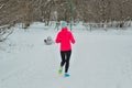 Winter running in park: happy woman runner jogging in snow, outdoor sport and fitness Royalty Free Stock Photo