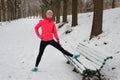 Winter running in park: happy woman runner warming up and exercising before jogging in snow, outdoor sport and fitness Royalty Free Stock Photo