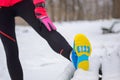 Winter running in park: sportswear closeup in snow, woman stretching before jog, outdoor fitness and sport