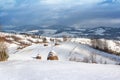 Winter rural landscape, haystacks on the background of snow-capped mountains Royalty Free Stock Photo