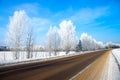 Winter rural landscape with the road the forest and the blue sk