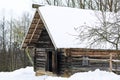 Winter Russian landscape. An old wooden hut, a log house with a thatched roof. Log house with barn. Royalty Free Stock Photo