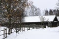 Winter Russian landscape. An old wooden hut, a log house with a thatched roof. Log house with a wooden wicker fence. Royalty Free Stock Photo