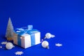 Winter sale. White gift box with blue ribbon, winter tree, Snowflakes and Silver balls in Christmas composition on blue background Royalty Free Stock Photo