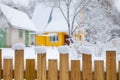 Winter scene in the countryside. Wooden fence in snow and wooden house at background. Close up with bokeh