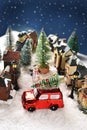 Winter scene decoration with houses in small town on Christmas night with a red car with a Christmas tree on the Royalty Free Stock Photo