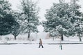 Winter scene outdoors. Man walking under snow in park. Heavy snowfall and snowstorm. Snow blizzard and bad weather winter