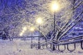 Winter scene. Snowfall in night park with lanterns. Christmas background. Snowflakes fall on snow. Royalty Free Stock Photo