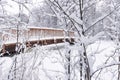 Winter scene with a wooden bridge crossing a frozen river in Northern Europe. It has just snowed.