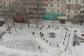 Winter scene on the yard from a bird`s eye view. An unidentified woman plays on the playground with children. A woman walks with