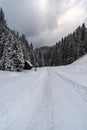 Winter scenery with snow covered road, forest, hill on the background and small wooden shelter Royalty Free Stock Photo