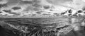 Winter sea in black and white panoramic view with intense clouds paints sky and wavy water with lot of sea foam