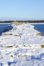 Winter seascape, port entrance with snow covered concrete breakwater