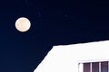 Winter season at night, a rooftop covered in a thick layer of snow with stars and a full moon, christmas background Royalty Free Stock Photo