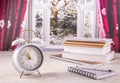 Winter semester, time management concept. Alarm clock with book, notenooks with open window in background