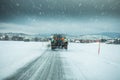 Winter service truck or gritter spreading salt on the road surface to prevent icing in stormy snow winter day.