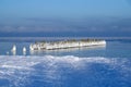 Wooden piles of the old pier covered with ice in frosty winter weather