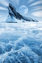 Winter Siberian landscape. Lake Bakal. Transparent patterned ice surface and mighty rock. Frosty blue image. Royalty Free Stock Photo