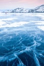 Winter Siberian landscape. Mountains and clear ice with cracks on Lake Baikal.