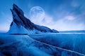 Winter Siberian landscape. Ogoy Island on Lake Baikal. Transparent patterned ice surface and mighty rock in moonlight.