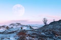 Winter Siberian landscape. Rocks on Lake Baikal against the background of the sunset and the moon.