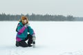 Winter sitting on haunches hiker with metal drink flask resting at snowy landscape background