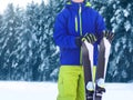 Winter skier teenager sportsman in sportswear with ski standing on snow over snowy forest