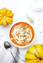 Winter slow food. Pumpkin carrot soup with cream, seeds and thyme.. Healthy diet food. White soup bowl on gray table background.