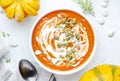 Winter slow food. Pumpkin carrot soup with cream, seeds and thyme.. Healthy diet food. White soup bowl on gray table background.