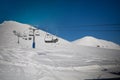 Ski lift empty ropeway on hilghland alpine mountain winter resort on bright sunny evening . Ski chairlift cable way with people Royalty Free Stock Photo