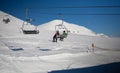 Ski lift empty ropeway on hilghland alpine mountain winter resort on bright sunny evening . Ski chairlift cable way with people Royalty Free Stock Photo