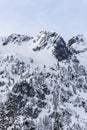 Winter Snow Covered Mountain Summit Peak with Rocky Cliffs on Sunny Day